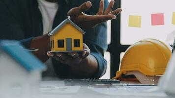 mani di architetto o ingegnere Lavorando su planimetria incontro per progetto Lavorando con compagno su modello edificio e ingegneria utensili nel Lavorando luogo, costruzione e struttura concetto. video