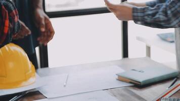 mani di architetto o ingegnere Lavorando su planimetria incontro per progetto Lavorando con compagno su modello edificio e ingegneria utensili nel Lavorando luogo, costruzione e struttura concetto. video