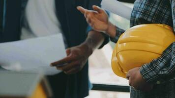 mani di architetto o ingegnere Lavorando su planimetria incontro per progetto Lavorando con compagno su modello edificio e ingegneria utensili nel Lavorando luogo, costruzione e struttura concetto. video