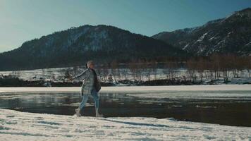 Cheerful woman runs near the river in winter and laughs. video