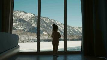 ein klein Kind nähert sich das Fenster beim Zuhause während selbst Isolation. video