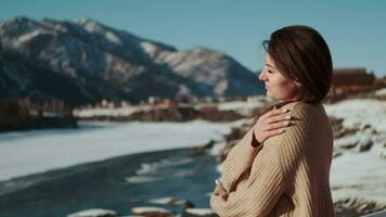 A woman stands on a balcony and relaxes against the backdrop of mountains in winter. video