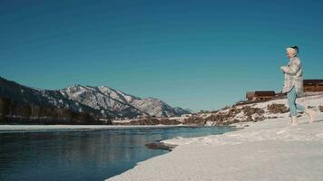 femme blogueur voyageur fait du une vidéo en utilisant une téléphone intelligent tandis que permanent dans le montagnes près le rivière. video