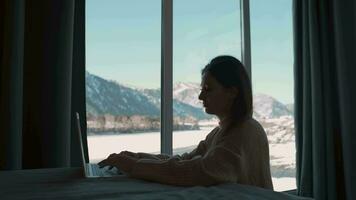 vrouw freelancer werken van huis zittend in de slaapkamer door de venster. video