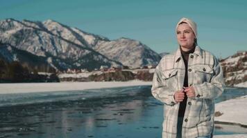 A beautiful woman walks near a river in a mountainous area in winter. video