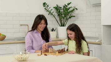 Cheerful daughter wins mom in chess and rejoices while sitting at the table at home. video