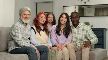 Portrait of a happy multi ethnic family of different age generations at home on the sofa. video