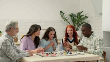 multi ethnique famille de différent âge générations jouer planche Jeu à Accueil séance à le tableau. le africain américain papa jette le dé sur le table et perd. video