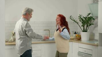 aimant Sénior couple 50-60 ans vieux pendant une amusement Danse dans le cuisine. video