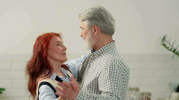 Loving senior couple 50-60 years old slow dance at home in the kitchen. video