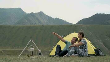 aimant couple se détendre dans la nature dans de face de le tente dans ensoleillé temps. video