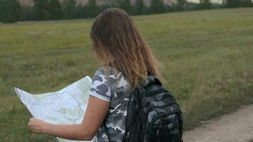 lindo mulher turista com uma mochila e com uma mapa dentro mão carrinhos em uma fundo do montanhas. Câmera rotação por aí video
