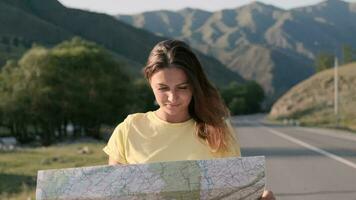 Portrait. Attractive female tourist with a map in hands travels walking on the highway in a good mood video