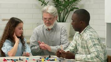 multi etnisch familie van verschillend leeftijd generaties Speel bord spel Bij huis zittend Bij de tafel. opa gooit de Dobbelsteen Aan de tafel en wint. video