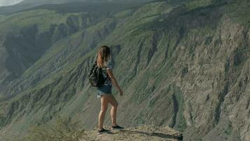 exitoso mujer viene a el acantilado de el montaña y levanta su manos arriba. el camino a éxito y felicidad. video