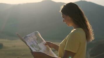 portrait. femelle touristique des stands sur le bord de une falaise avec une carte dans sa mains et regards pour une route pour Voyage video