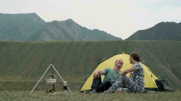 amorevole coppia rilassare nel natura nel davanti di il tenda. uomo e ragazza siamo Lavorando e baci video