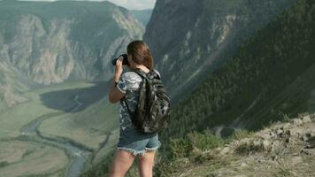 Female traveler takes pictures with the camera while standing at the peak of the mountain. video