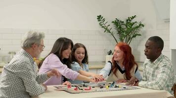 multi ethnique famille de différent âge générations jouer planche Jeu à Accueil séance à le tableau. mettre votre mains sur Haut de chaque autre et réjouir. video