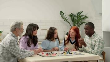 Multi Ethnic family of different age generations play board game at home sitting at the table. Dad throws the dice on the table and loses. video