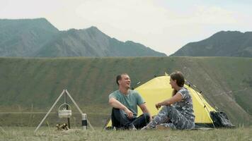 Loving couple relax and have fun outdoors in front of the tent in sunny weather. video