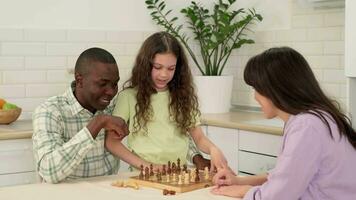 Multi ethnic family of three play chess at home sitting at the table. video