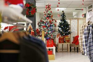 Christmas tree and lights at mall festive apparel boutique decorated for gifts shopping spree at retail center. Christmas themed clothing store waiting for buyers throughout wintertime festivities. photo