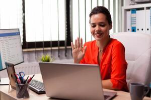 Businesswoman talking with team using internet connection during online meeting. Entrepreneur using internet connection for video meeting with coworkers looking at webcam. photo