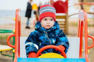 baby sitting at the wheel of a children's car on the playground photo