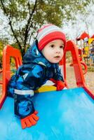 baby sitting at the wheel of a children's car on the playground photo