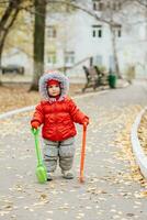 un pequeño niño con un rastrillo y un pala camina en el parque foto