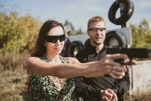 un niña aprende a disparar un pistola a un disparo rango con un instructor foto