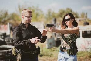 un armas instructor enseña un niña a disparar un pistola a un disparo rango foto