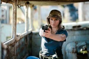 un mujer con un pistola en su mano sufre militar formación a un formación suelo y aprende a disparo. foto