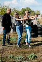 A weapons instructor teaches a girls to shoot a pistol at a firing range photo