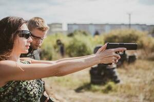 A weapons instructor teaches a girl to shoot a pistol at a firing range photo