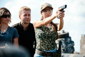 A weapons instructor teaches a girls to shoot a pistol at a firing range photo