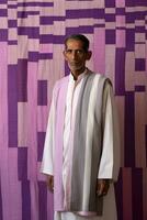 AI generated A Man in a Colorful Long Robe, possibly a Sikh, standing in front of an intricate purple and pink wall. photo