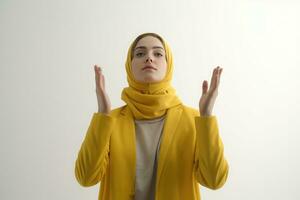 AI generated A Muslim woman in a yellow headscarf praying with her hands raised photo