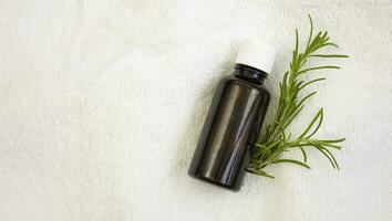 Bottle of rosemary oil on a white towel. Copy space photo