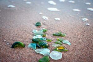 Sand beach and stones with foam concept photo. Glass stones from broken bottles polished by the sea. photo