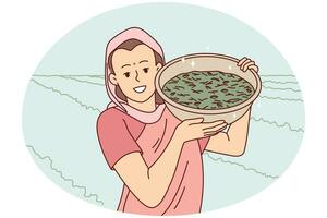 Smiling indian woman in traditional clothes show bowl working in field in countryside. Happy female worker collecting crop in rural grassland. Farming concept. Vector illustration.