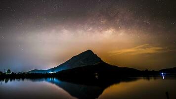 mjölkig sätt av klar himmel ovan berg reflektera på vatten i damm video