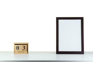 Wooden calendar 03 January with frame for photo on white table and background