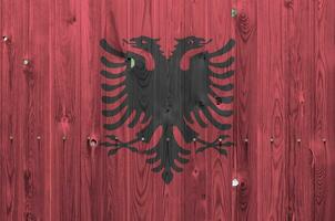 Albania bandera representado en brillante pintar colores en antiguo de madera pared. texturizado bandera en áspero antecedentes foto