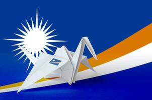 Marshall Islands flag depicted on paper origami crane wing. Handmade arts concept photo
