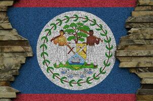 Belize flag depicted in paint colors on old stone wall closeup. Textured banner on rock wall background photo