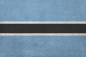 Botswana flag depicted in bright paint colors on old relief plastering wall. Textured banner on rough background photo