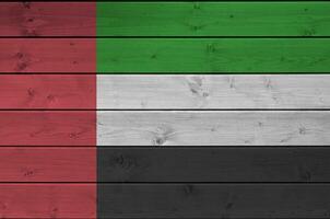 unido árabe emiratos bandera representado en brillante pintar colores en antiguo de madera pared. texturizado bandera en áspero antecedentes foto