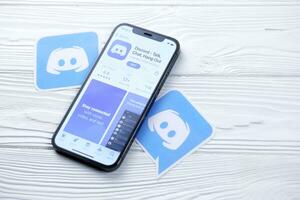 KHARKOV, UKRAINE - MARCH 5, 2021 Discord icon and application display screen on white table photo